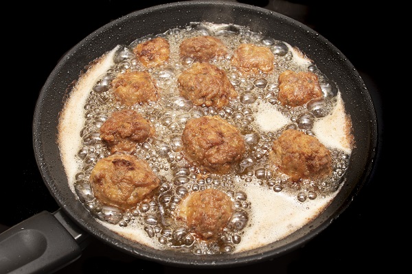 Round fries frying in bubbling oil, highlighting unhealthy fried foods.