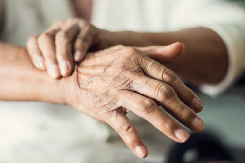 Close-up of elderly hands with wrinkles and joint discomfort, symbolizing Parkinson's health issues.