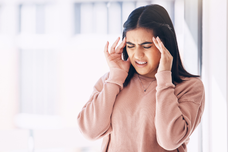 A woman with head pain, symbolizing an early sign of underlying health problems.