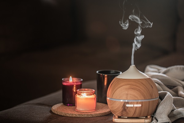 Wooden diffuser and glowing candles symbolize aromatherapy for better sleep in Parkinson's patients.