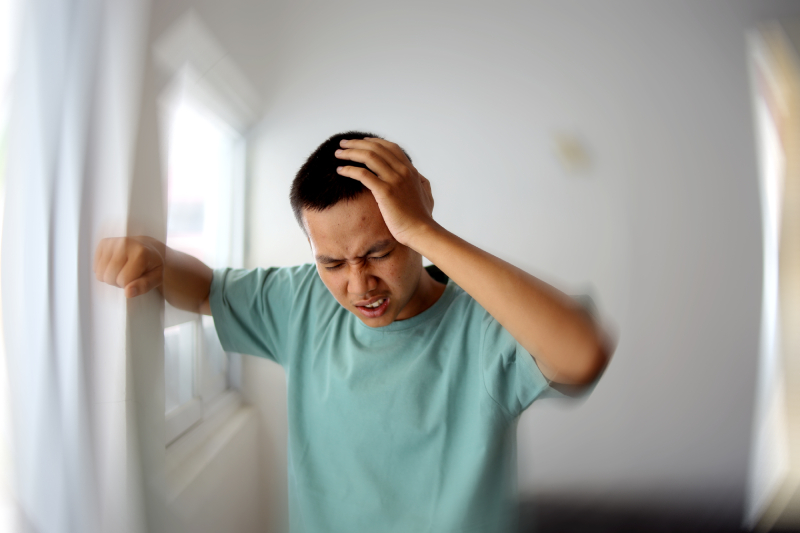 A man holding his head with closed eyes and dizziness reflects symptoms of epilepsy.