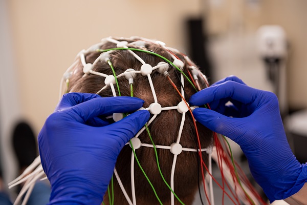 A professional prepares a patient for EEG brain testing to diagnose epilepsy.