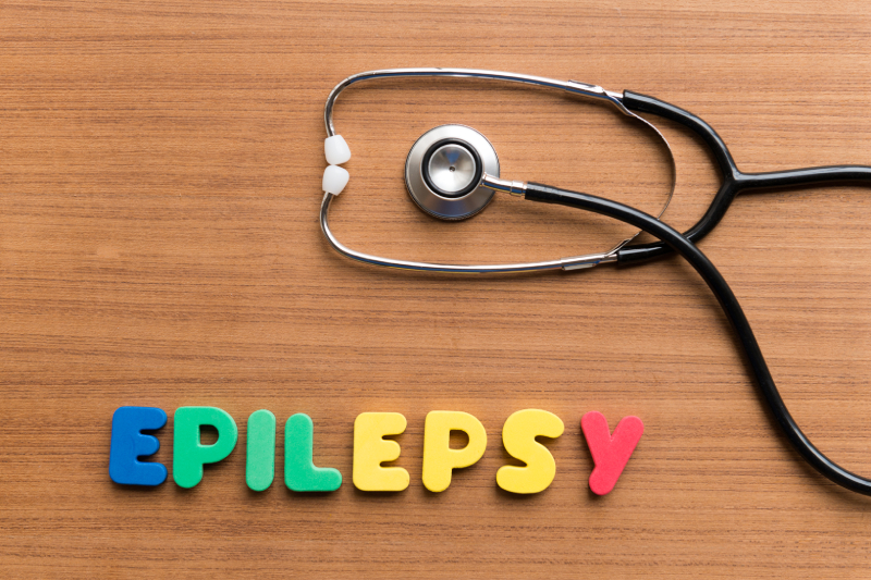 The word 'epilepsy' next to a stethoscope on a table represents a chronic, non-contagious neurological disorder.