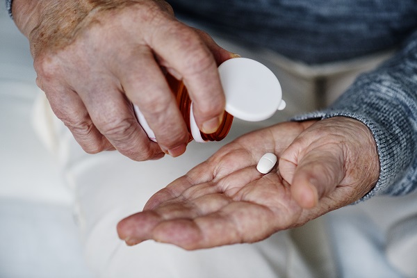 Elderly person taking medication shows how treatment can ease Parkinson -related pain.