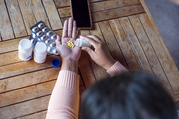 A person taking pills, surrounded by medication, illustrates how epilepsy treatment can ease pain.