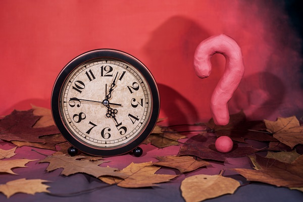 A clock and question mark on a table symbolize confusion from Alzheimer’s disease.